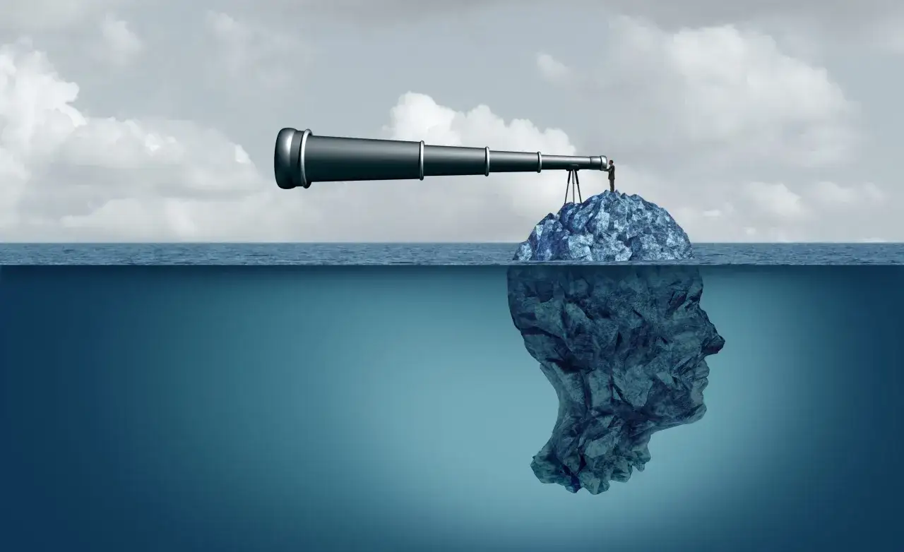 A man on an island uses a telescope, symbolizing self management and self leadership strategies. Below the surface, a stone head represents the inner self.