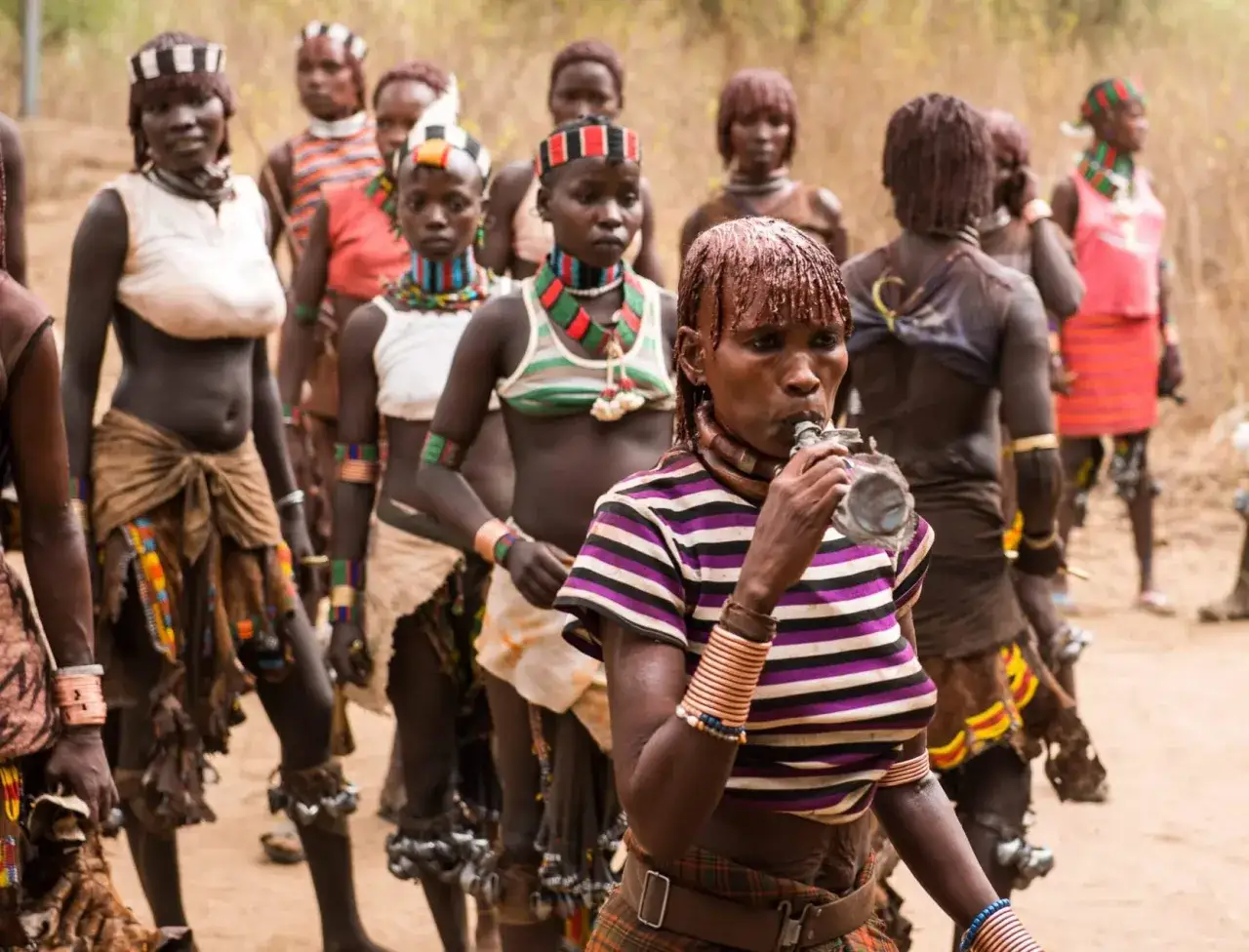 Donne Mursi in Etiopia, con ornamenti tradizionali e una che beve da una borraccia.