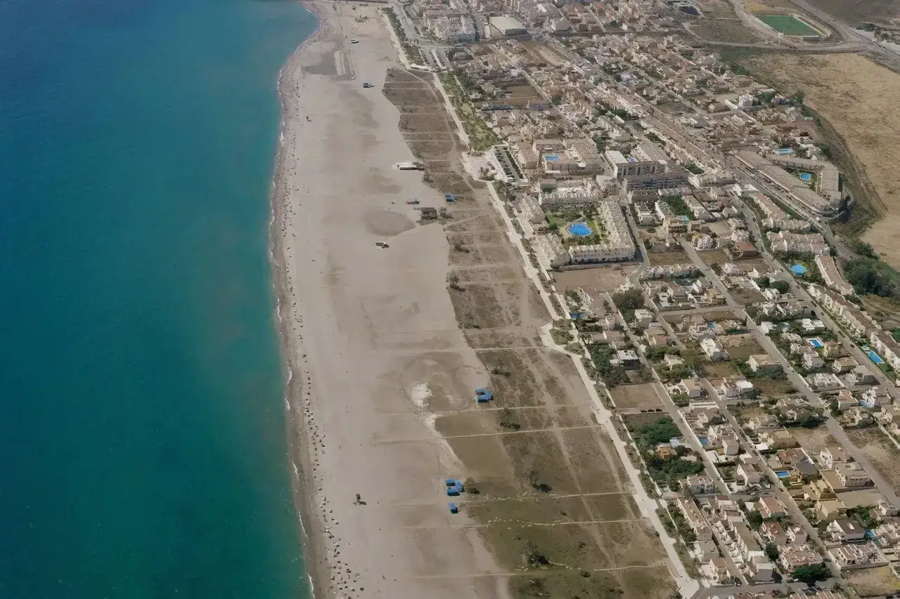 Vista aérea de la playa Las Marinas Vera, con el mar turquesa a la izquierda y la urbanización a la derecha.