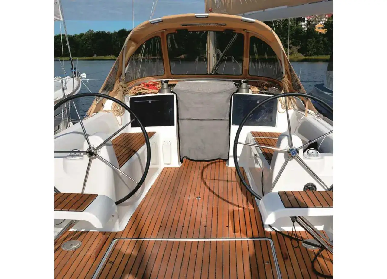Il ponte di uno yacht con due timoni, un tendalino e un tavolato in teak. Il boccaporto, un'apertura per l'accesso, &egrave; visibile sul ponte.