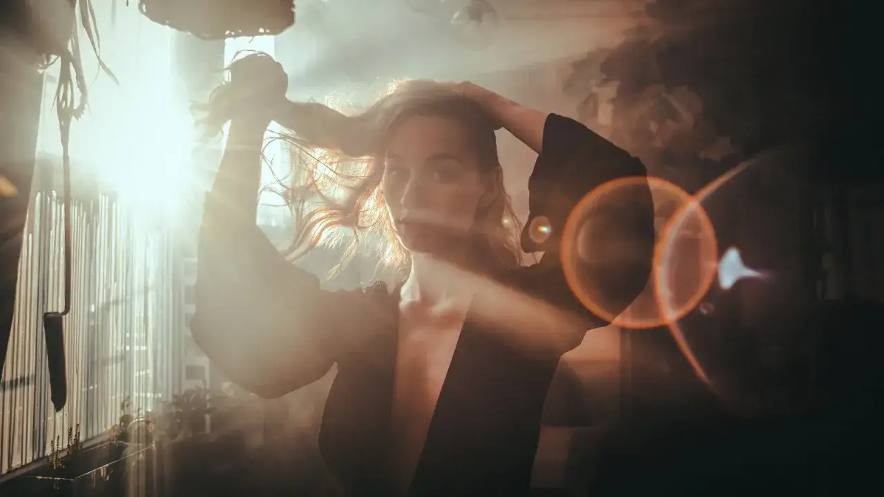 Une femme aux cheveux longs, baignée de lumière, une idée photo créative capturant un moment de grâce et de mystère.