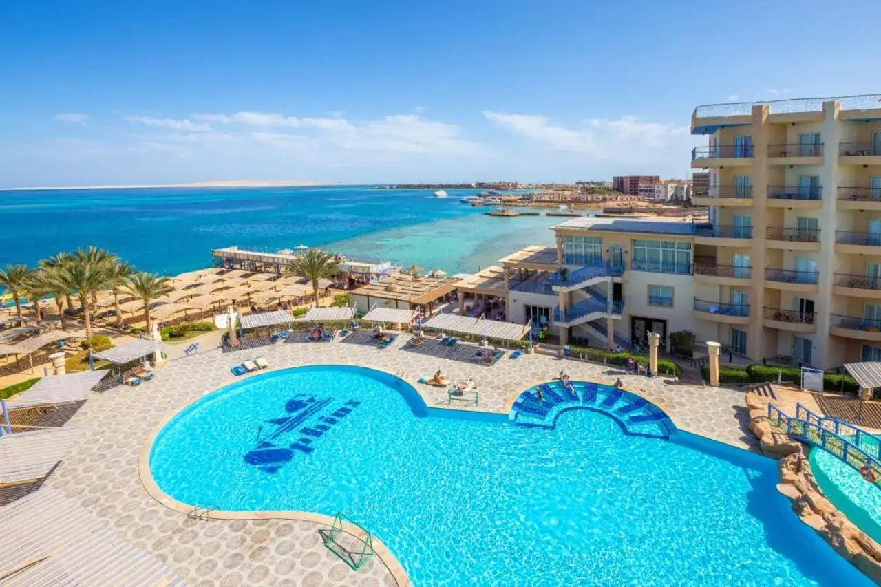 Basen w King Tut Resort z widokiem na morze, plażę z palmami i budynki hotelowe.