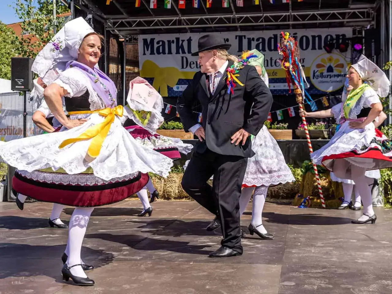 T&auml;nzer in Tracht bei einem Fest im Herbst. Die Frauen tragen wei&szlig;e Hauben und bunte R&ouml;cke, der Mann einen schwarzen Anzug.