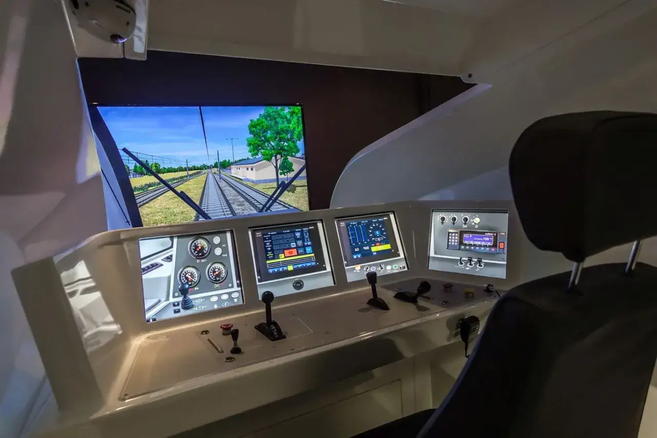 Symulator lokomotywy, idealny do nauki na **darmowy kurs na maszynistę**. Wnętrze kabiny z ekranem symulującym jazdę po torach.