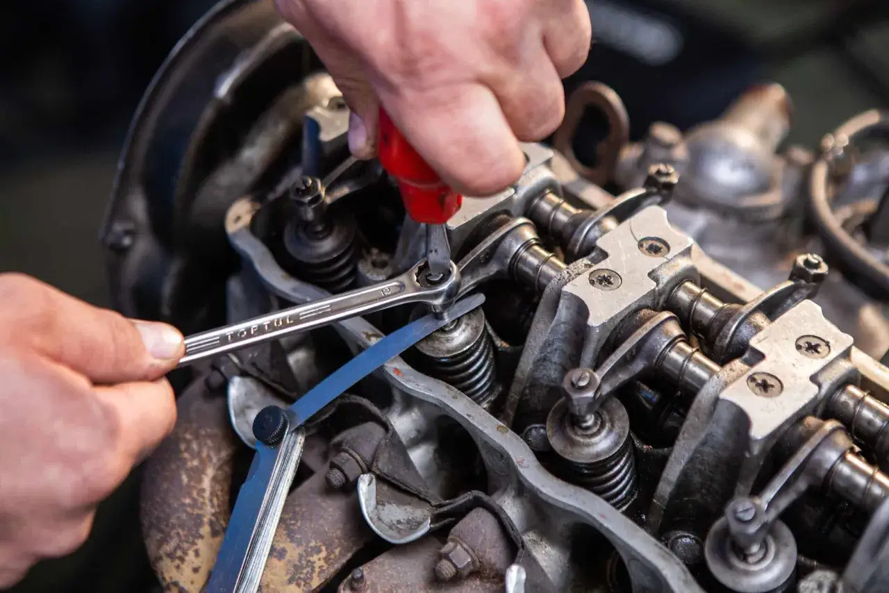 Mechanik reguluje luzy zaworowe kluczem i szczelinomierzem w silniku.