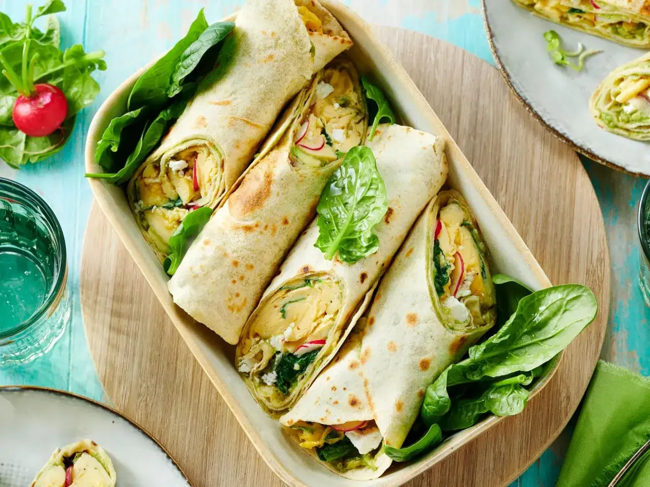 Herzhafte Tortilla-Wraps gefüllt mit Spinat, Feta und Rührei, garniert mit frischem Spinat und Radieschen.