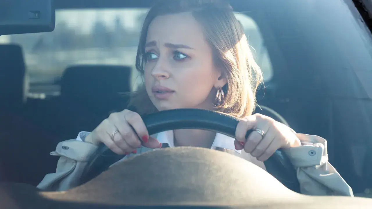 Ragazza con espressione preoccupata al volante, mentre cerca di superare la paura di guidare.