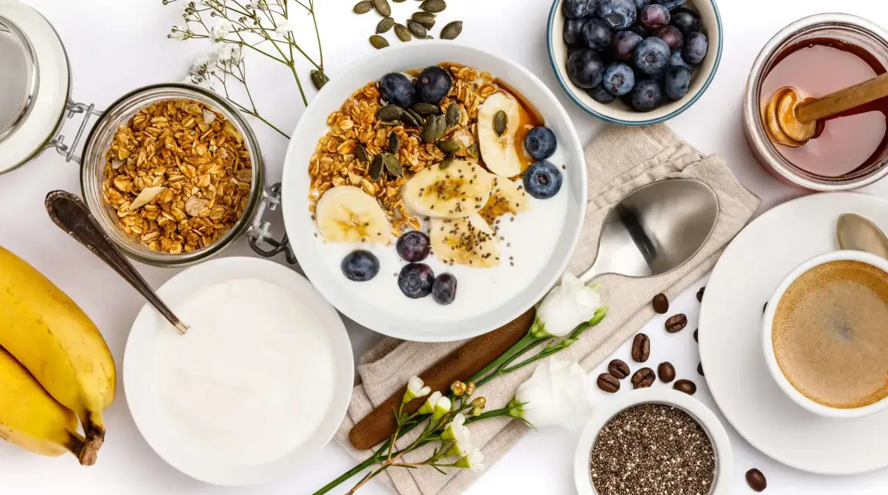 Un'idea sana e gustosa su cosa mangiare a colazione: yogurt, granola, frutta fresca, semi di chia e un caff&egrave;.