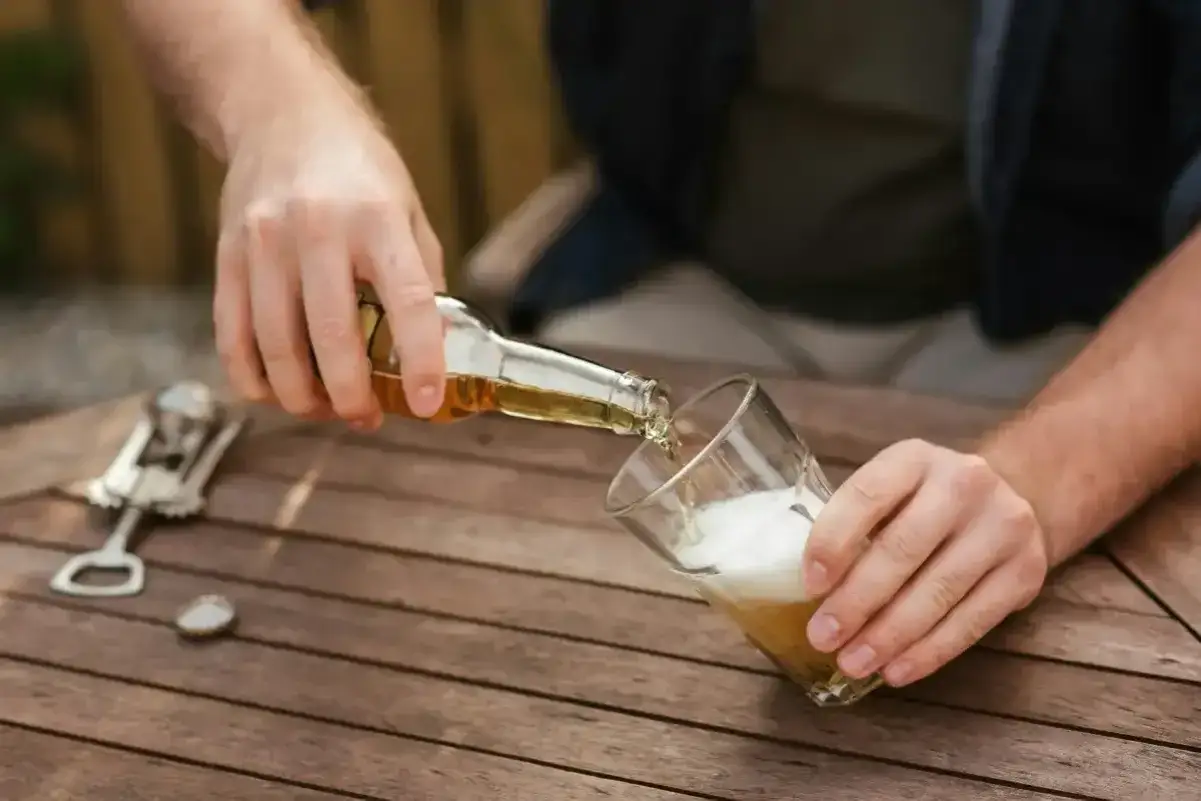 Mężczyzna nalewa piwo bezalkoholowe do szklanki. To ważny wybór dla alkoholika, który chce cieszyć się smakiem bez negatywnych konsekwencji.