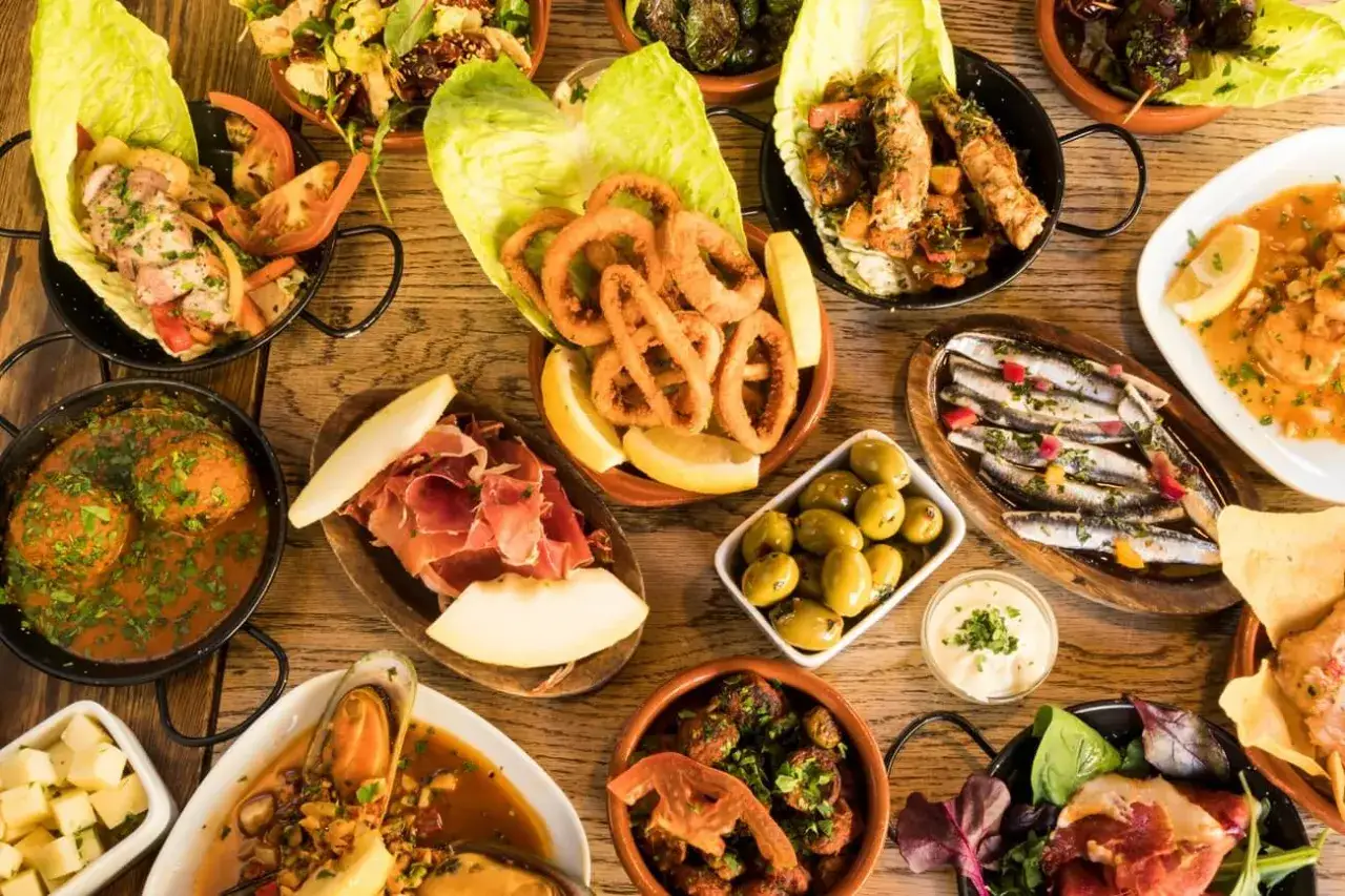 Vielfalt an Tapas: Tintenfischringe, Sardinen, Fleischb&auml;llchen, Schinken, Oliven und mehr &ndash; perfekt, um Tapas selber machen zu inspirieren.