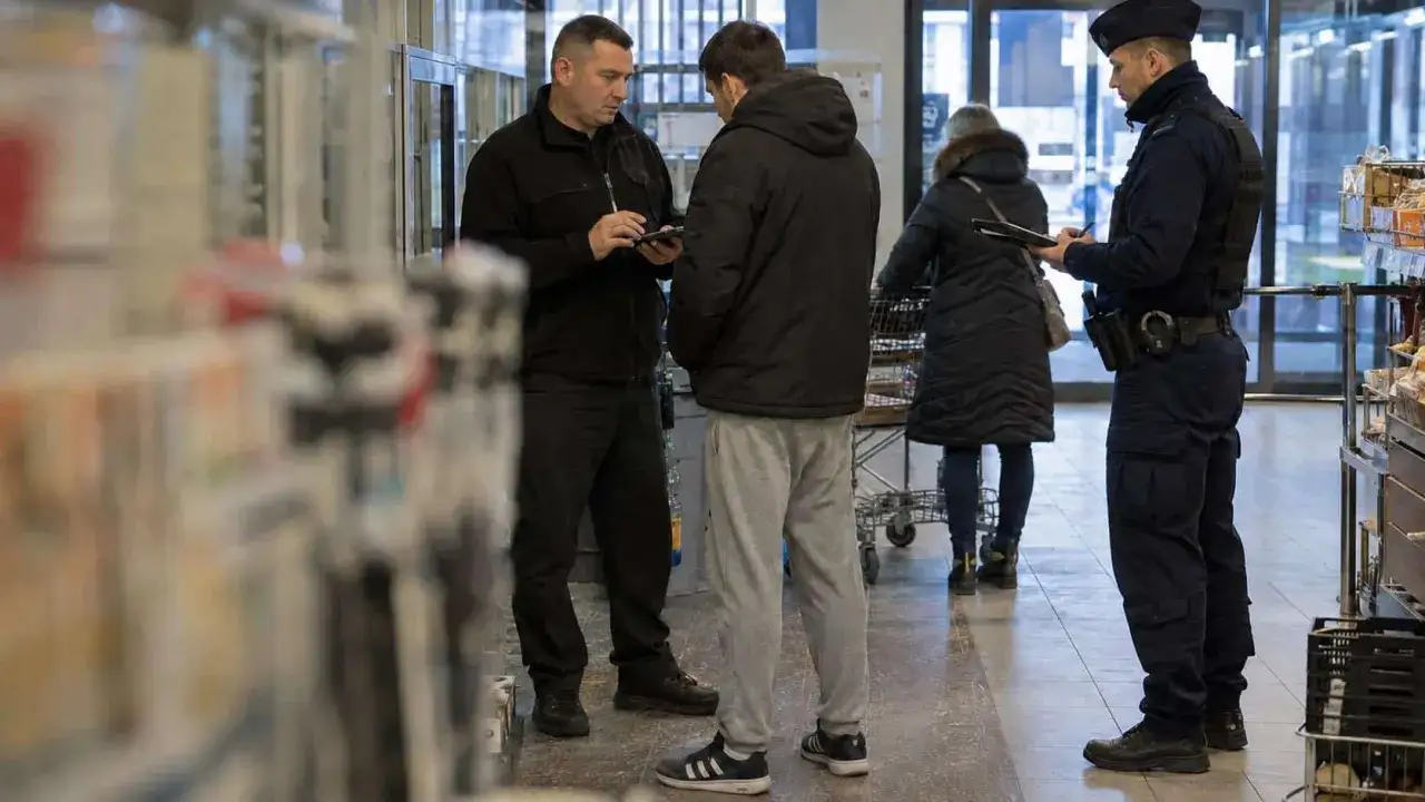 Ochroniarz w sklepie rozmawia z klientem, spisując dane. Obok stoi policjant, pilnując porządku. To sytuacja z artykułu 278 kk.