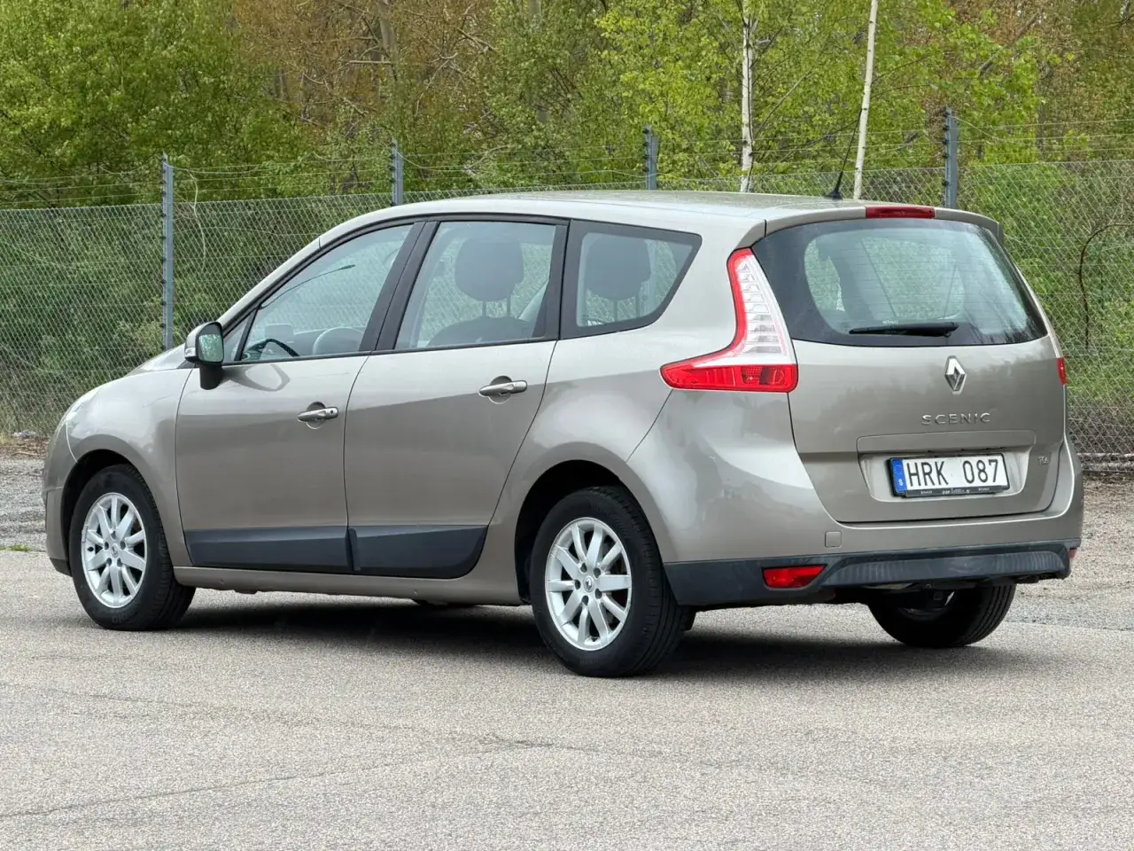 En beige Renault Grand Scénic står parkerad utomhus. Bilen har en svensk registreringsskylt.