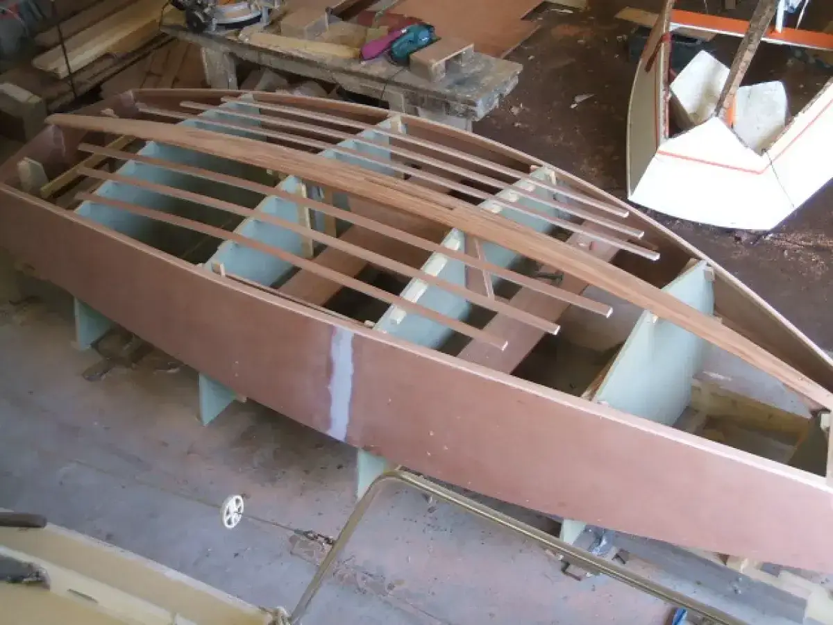 Construction d'un bateau en bois, la coque est en cours de montage avec des lattes de bois.