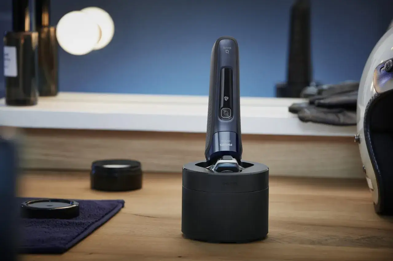 Elegancka golarka Philips 7000 Series na ładowarce, obok męskie kosmetyki i rękawice motocyklowe.