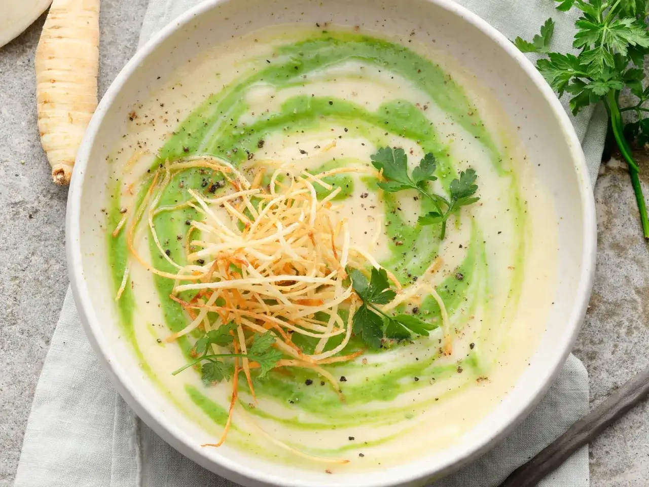 Cremige Petersilienwurzelsuppe mit grünen Wirbeln, knusprigen Streifen und Petersilie. Ein köstliches Petersilienwurzel Rezept.