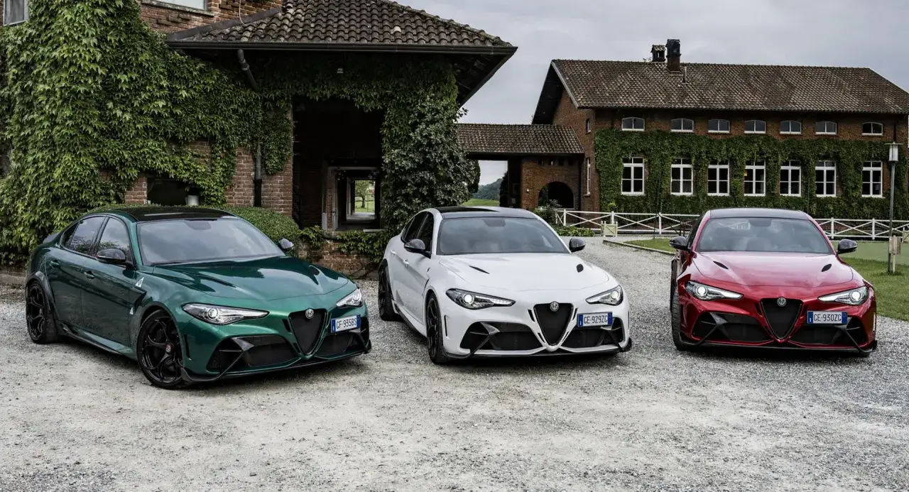 Trzy Alfa Romeo Giulia GTAm w kolorach zielonym, białym i czerwonym stoją przed zabytkowym budynkiem porośniętym bluszczem.