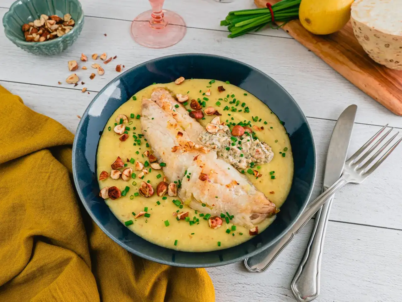 Un plat de poisson savoureux sur un lit de purée crémeuse, garni de noisettes croquantes et de ciboulette. Une recette poisson qui invite à la gourmandise.