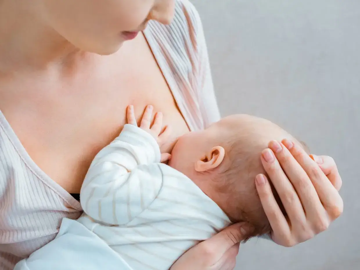 Un neonato si nutre al seno materno, ricevendo il prezioso colostro, un alimento fondamentale per la sua crescita.