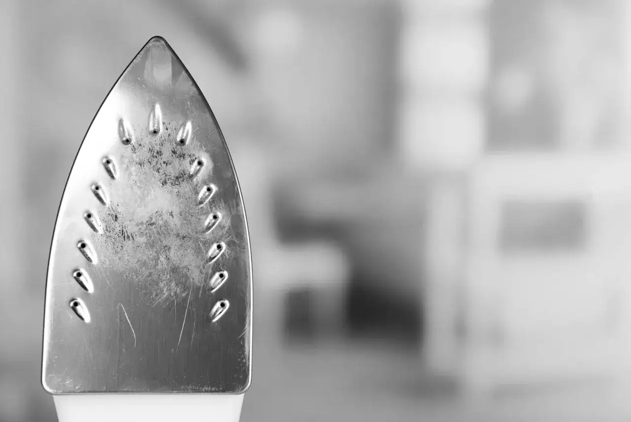 Metalowa stopa żelazka z widocznymi śladami kamienia. Dowiedz się, jak odkamienić żelazko, by znów działało jak nowe.