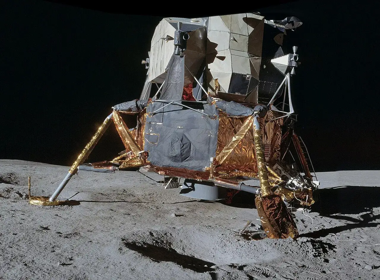 Moduł księżycowy programu Apollo na powierzchni Księżyca. Złote i szare osłony odbijają światło.