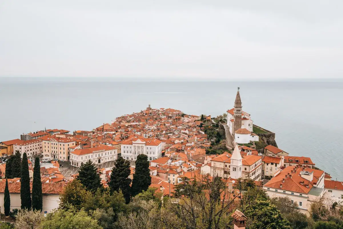 Piran: malerische K&uuml;stenstadt mit roten D&auml;chern und Kirchturm. Entdecke Piran Geheimtipps f&uuml;r deinen Urlaub an der Adria.