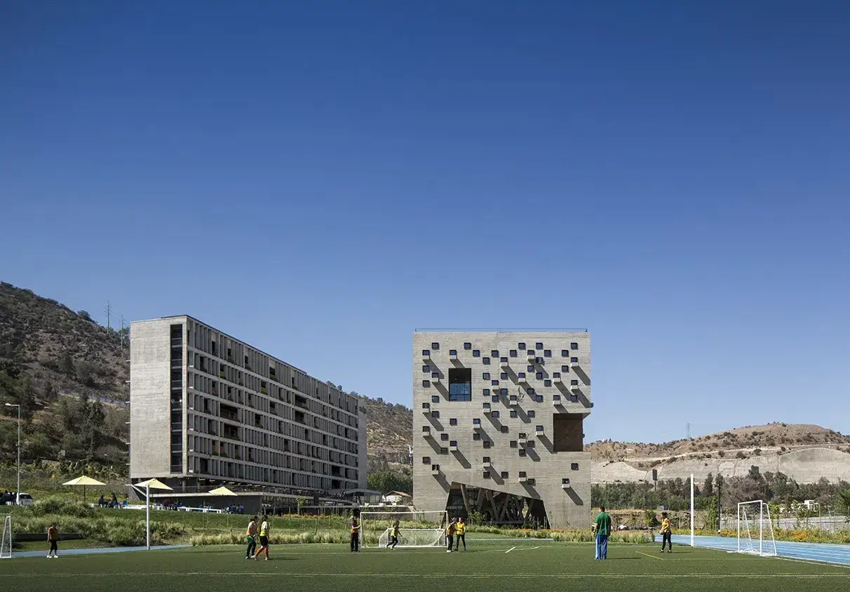 B&acirc;timents modernes sur le campus de l'universit&eacute; pontificale catholique du Chili, avec un terrain de football en premier plan.