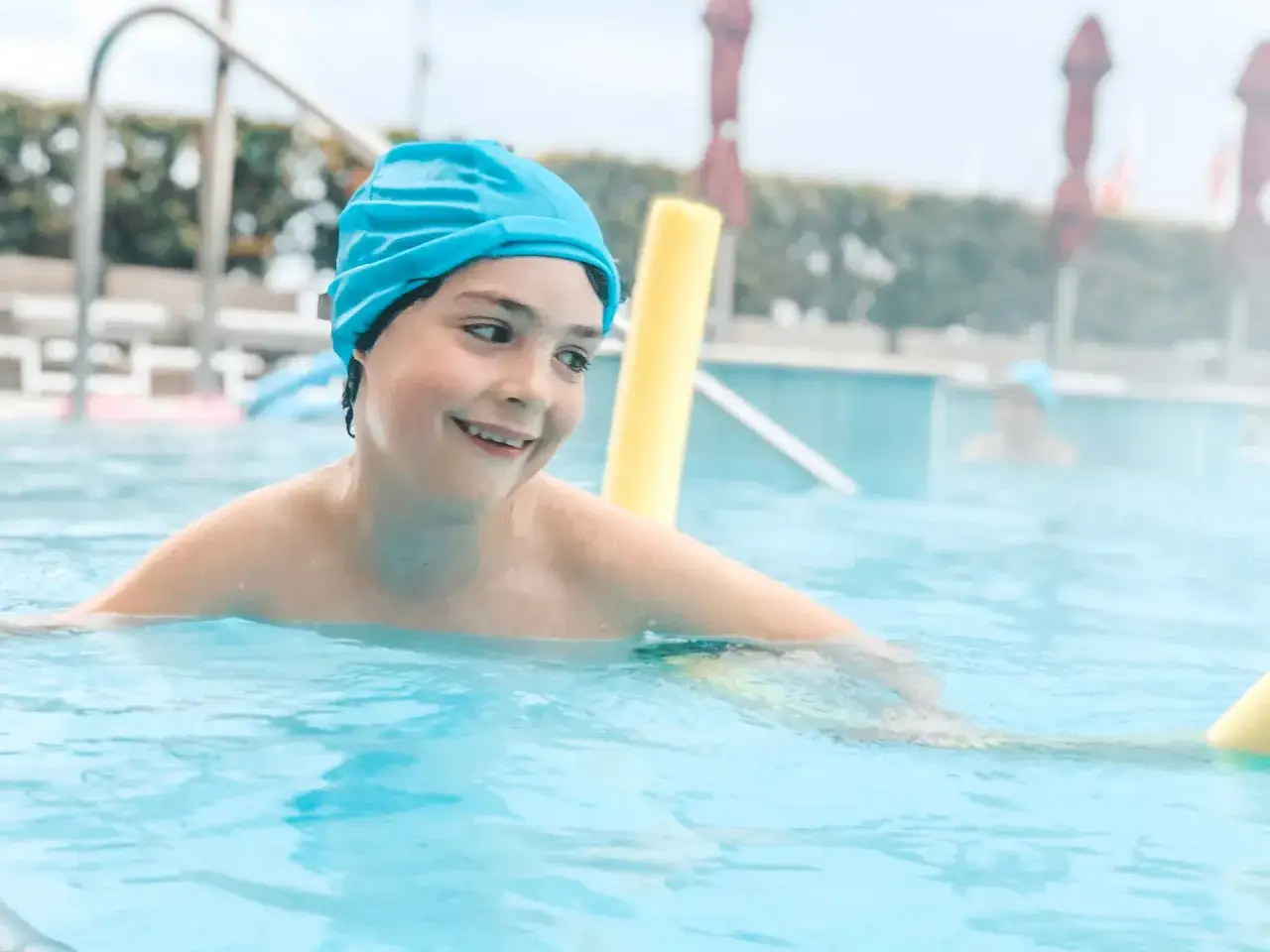Bambino sorridente con cuffia blu in piscina, un'ottima giornata alle terme Sirmione per i bambini.