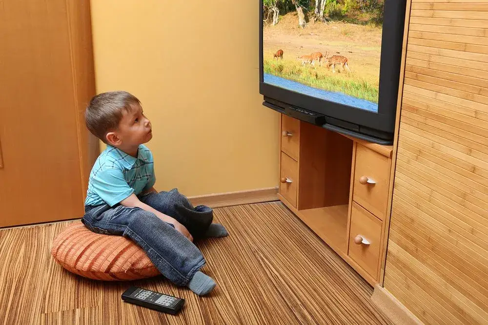 dziecko siedzące blisko telewizora