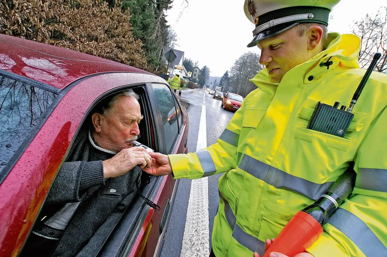 Polizist f&uuml;hrt Alkoholtest bei Fahrer durch. Die Probezeit f&uuml;r Alkohol am Steuer ist ernst.