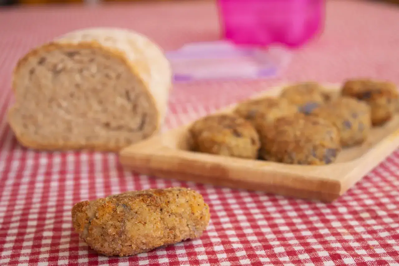 Polpette di melanzane siciliane dorate e croccanti, pronte per essere gustate con pane fresco.