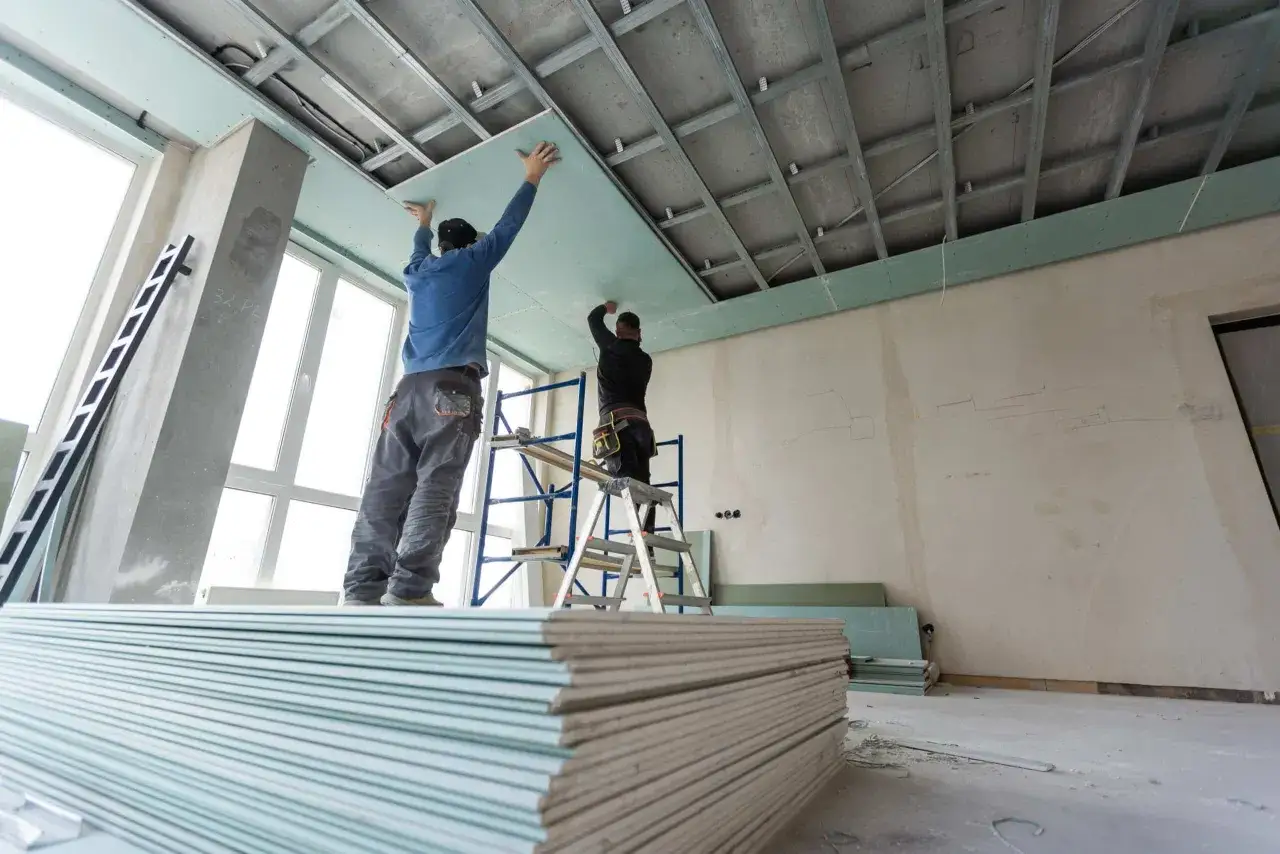Pose de suspente et fourrure au plafond par des ouvriers. Des plaques de pl&acirc;tre sont pr&ecirc;tes &agrave; &ecirc;tre install&eacute;es.