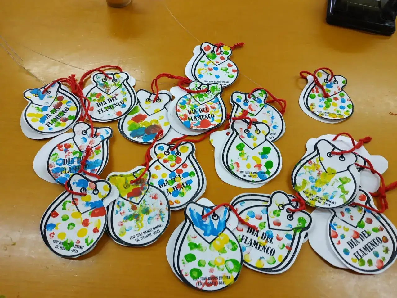 Manualidades flamencas para ni&ntilde;os: casta&ntilde;uelas de papel decoradas con huellas dactilares de colores.