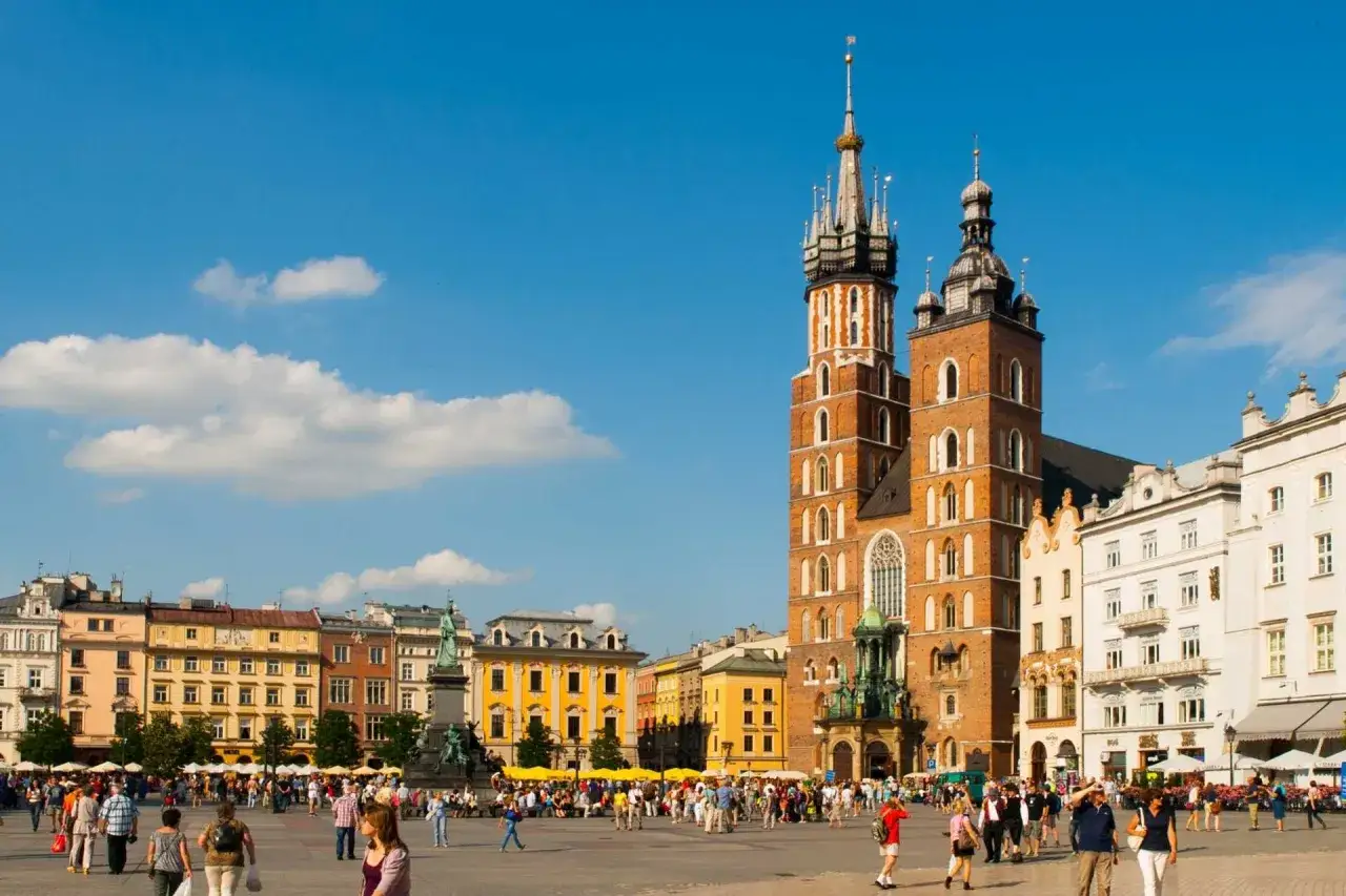 Tłum ludzi na Rynku Gł&oacute;wnym w Krakowie, w tle Bazylika Mariacka. Idealne miejsce na weekend w Krakowie.