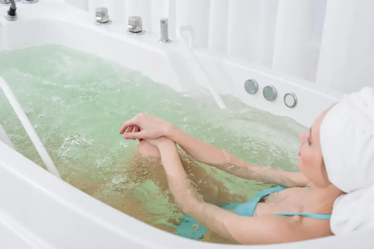 Kobieta relaksuje się w wannie z hydromasażem. To właśnie jest hydroterapia – co to jest? To leczenie wodą.