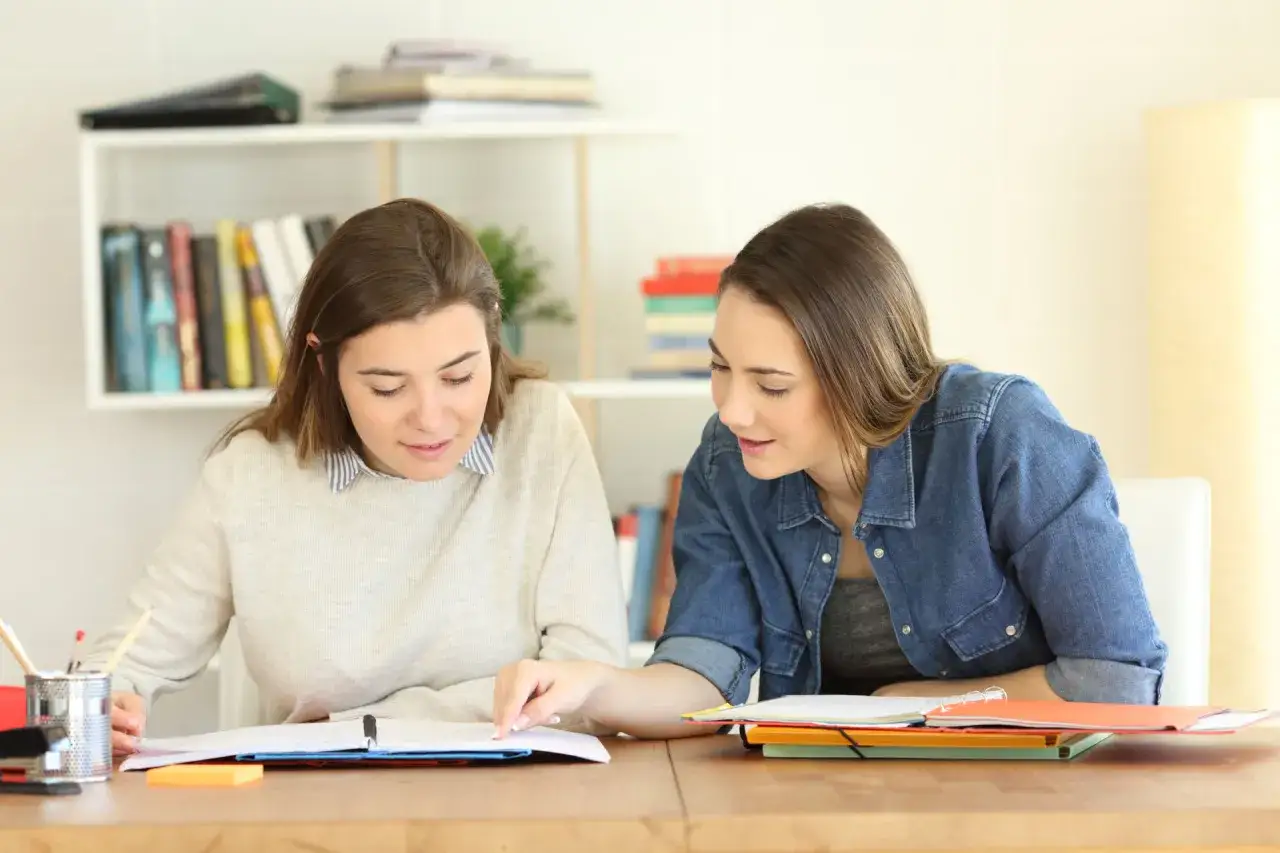 Zwei Studentinnen lernen gemeinsam. Sie sind konzentriert und arbeiten an ihren Unterlagen, um ihr Studium und ihre Teilzeitjobs zu meistern.