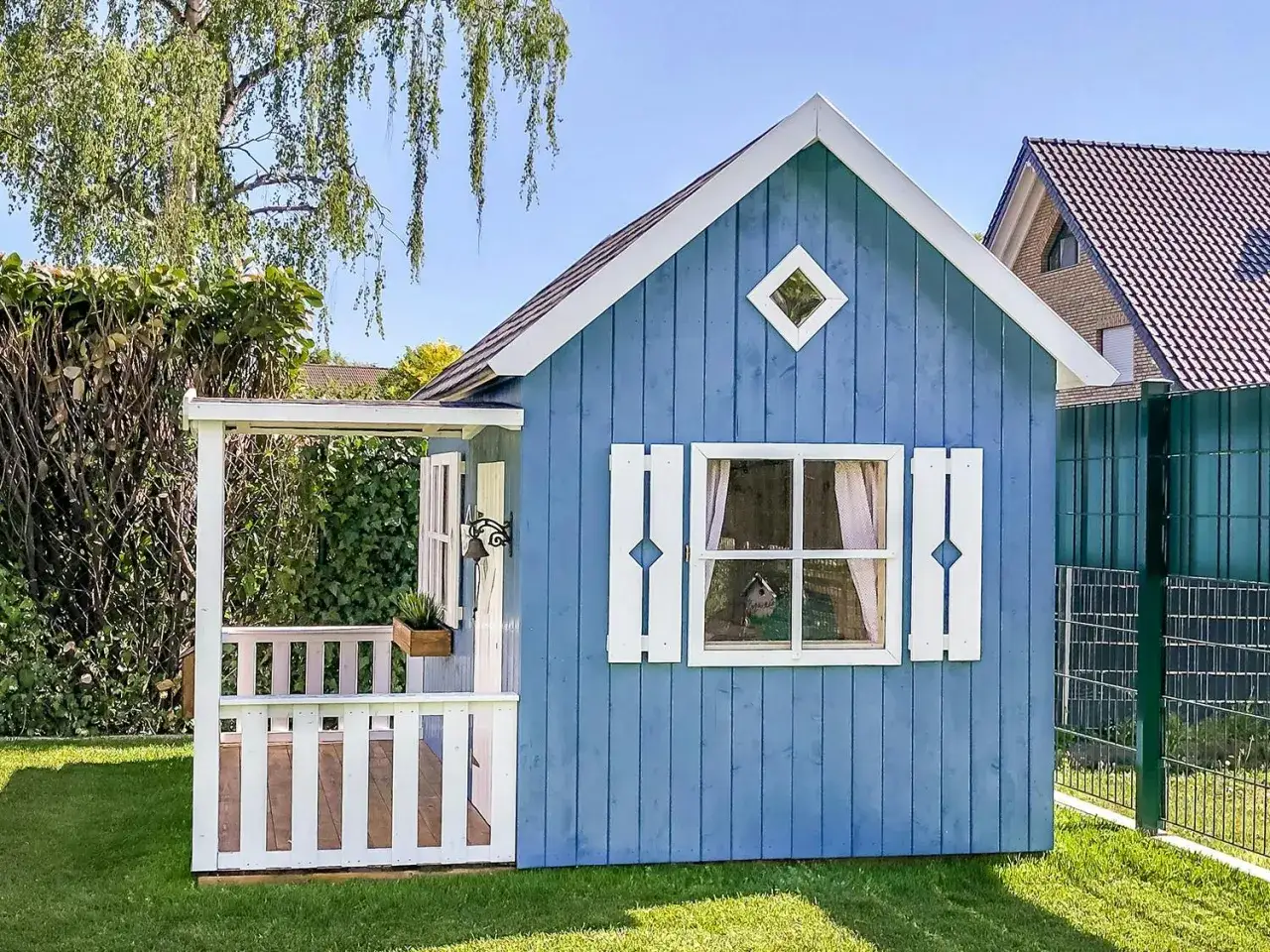 Blå lekstuga med veranda, perfekt för barn att leka i. En dröm att bygga lekstuga till sina barn.