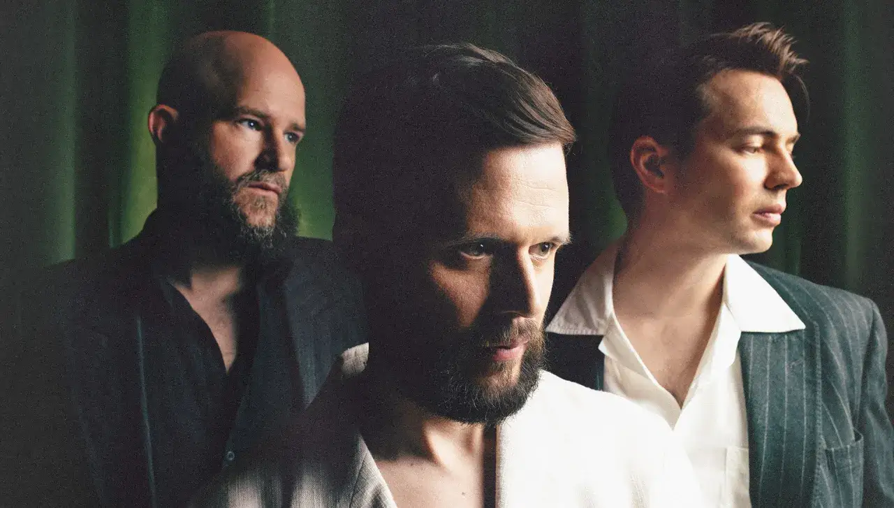 Trzech mężczyzn w garniturach, gotowych na white lies koncert.