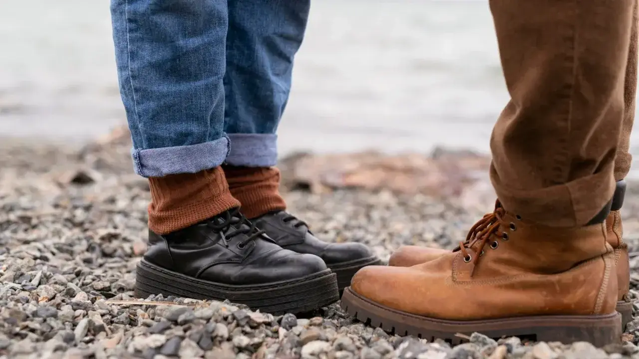 Jak zabezpieczyć nowe buty skórzane? Dwie pary butów na kamienistym podłożu, jedna czarna, druga brązowa.