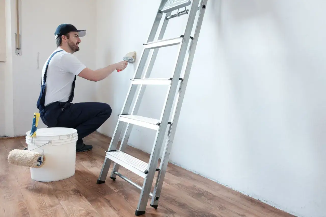 Pittore con pennello e secchio di pittura isolante, pronto a rinnovare le pareti.