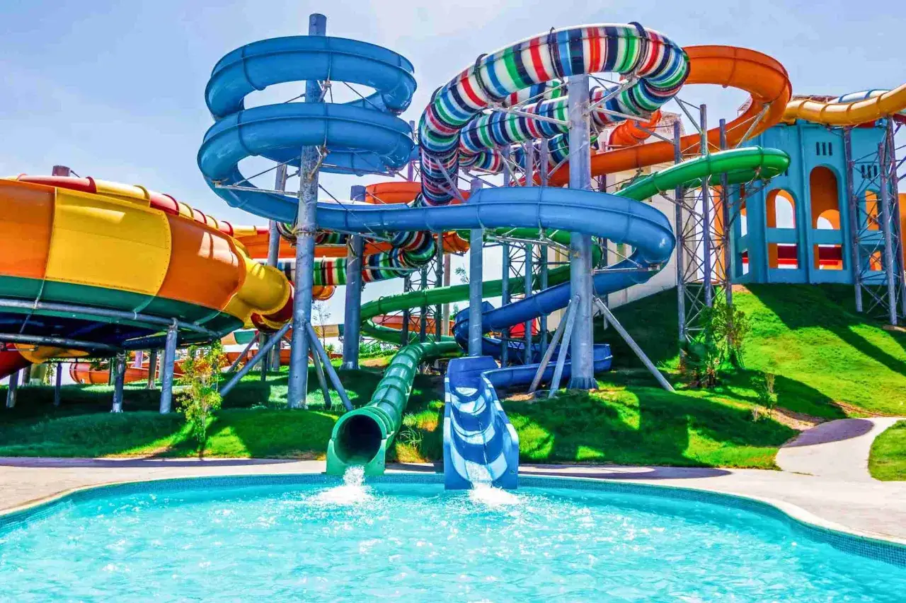 Bunte Wasserrutschen im Wasserpark, die zu einem Pool führen. Ein Ort der puren Freude und des Sommers, wie im Serenity Alma Heights.