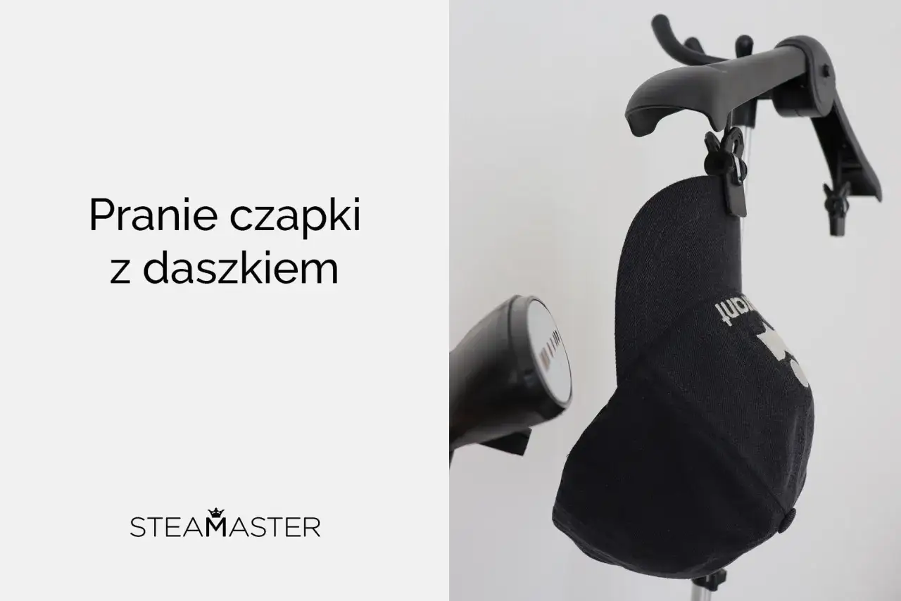 Czarna czapka z daszkiem wisi na wieszaku, obok parownicy. Dowiedz się, jak prać czapki z daszkiem.