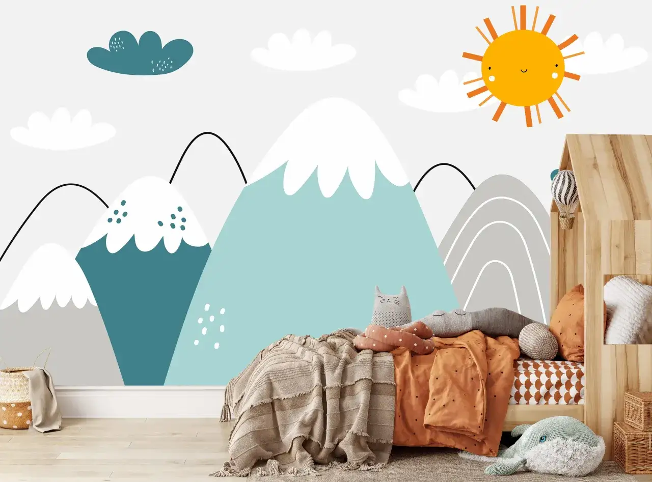 Un dormitorio infantil con una pared decorada con un mural de monta&ntilde;as nevadas, nubes y un sol sonriente. La cama est&aacute; vestida con mantas y cojines de animales.