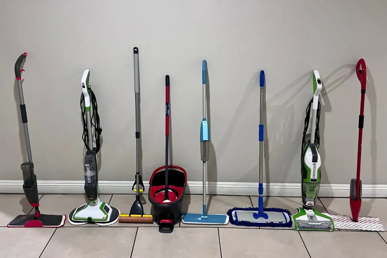 Various mops and cleaning tools are lined up. To keep vinyl floors looking great, consider how often you should mop vinyl floors based on traffic and spills.