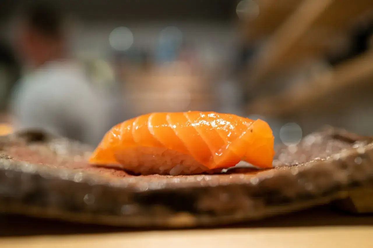 En utsökt laxnigiri på en rustik tallrik, en perfekt bit sushi att njuta av i sushi Stockholm city.