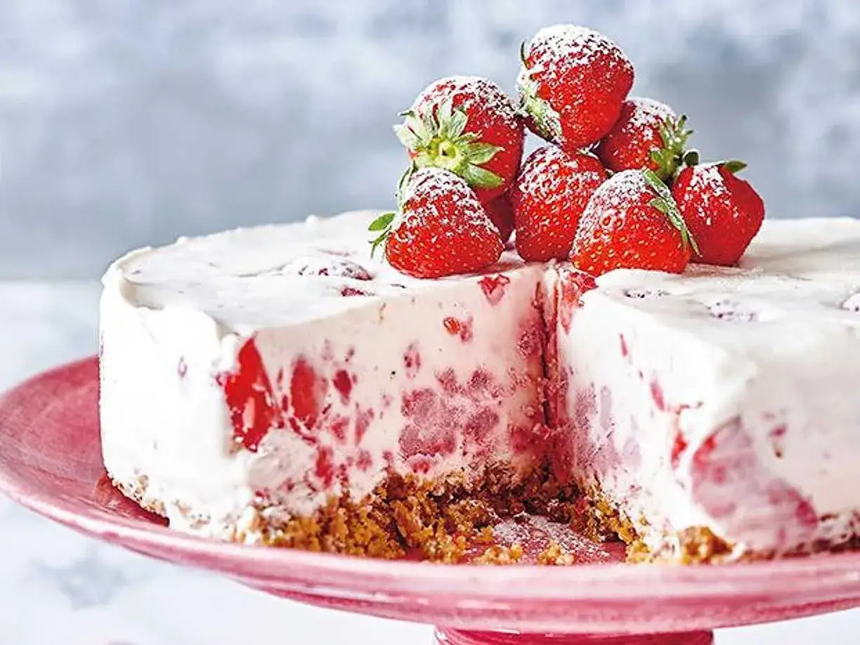 En kr&auml;mig jordgubbs cheesecake med f&auml;rska jordgubbar p&aring; toppen, pudrad med florsocker. En h&auml;rlig sommardessert.