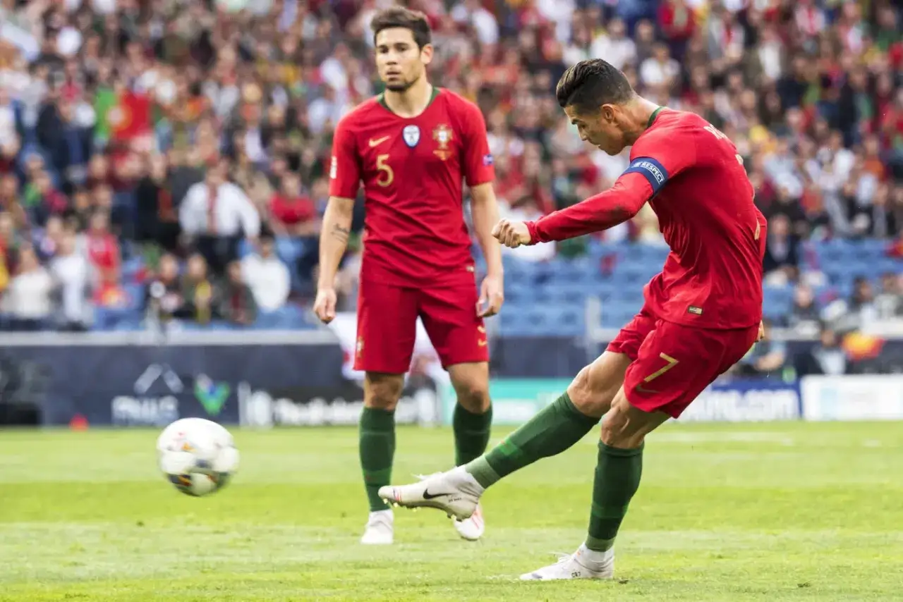 Piłkarz Cristiano Ronaldo z Portugalii strzela gola, podczas gdy jego kolega z drużyny obserwuje. Mecz Portugalia vs Szwajcaria.