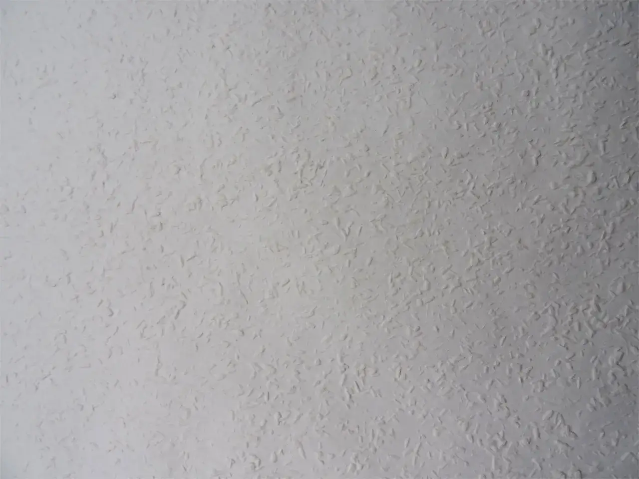 Eine weiße Raufasertapete mit feiner Körnung, die verschiedene Arten von Raufasertapeten zeigt.