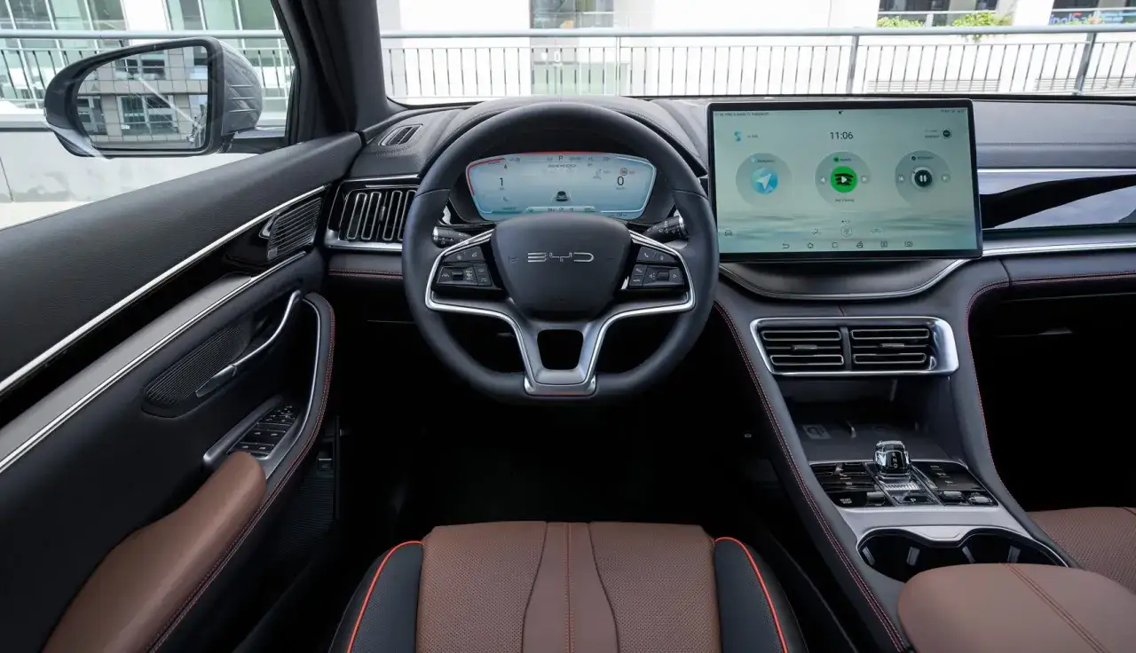 Interior de un BYD Seal con asientos de cuero marr&oacute;n y costuras rojas. La pantalla t&aacute;ctil central muestra el sistema de infoentretenimiento, ofreciendo una experiencia de conducci&oacute;n c&oacute;moda y moderna.