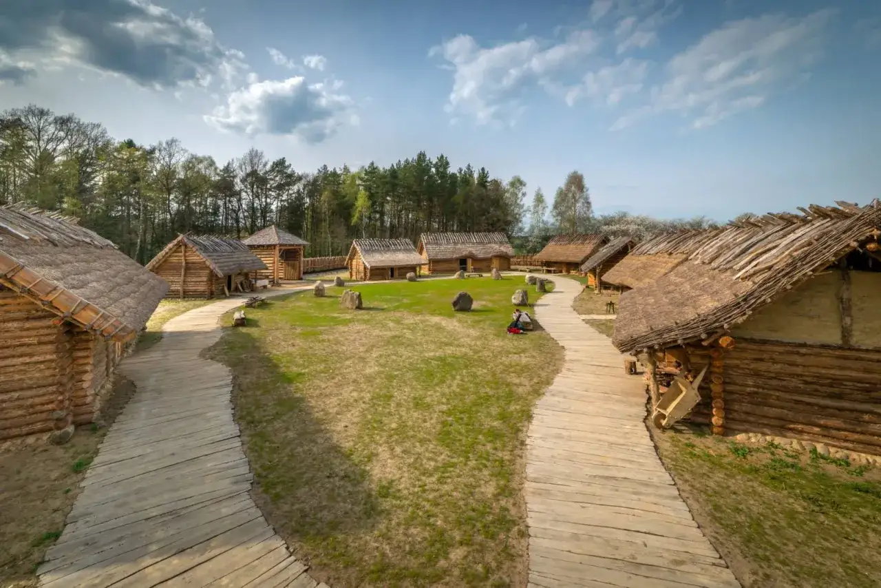 Sławutowo atrakcje: drewniane chaty kryte strzechą, kamienie i ścieżki tworzą klimat dawnej osady.