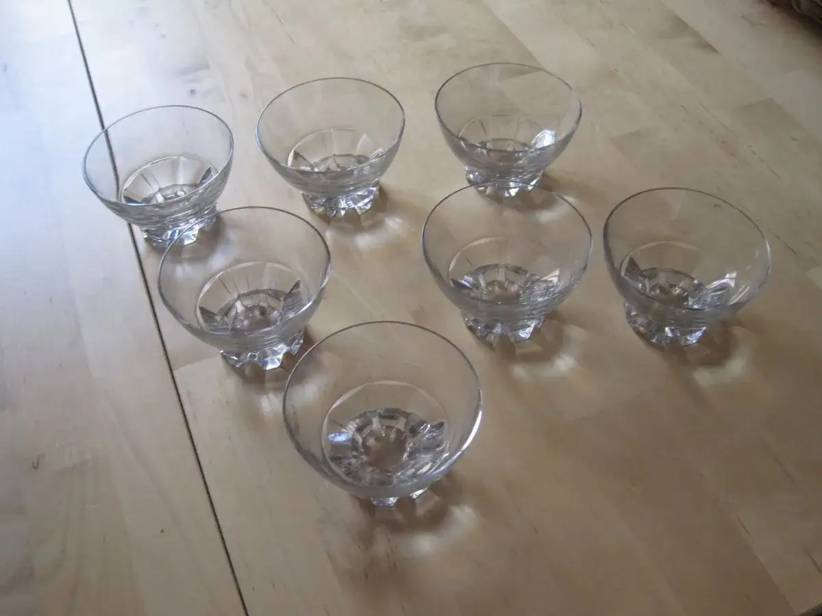 Sept verres à pied en cristal, forme coupe, prêts pour une dégustation de champagne ou un dessert.